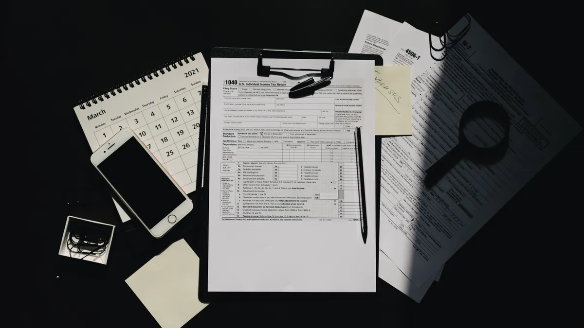 Audit-style desk with papers, calendar, phone, and magnifier