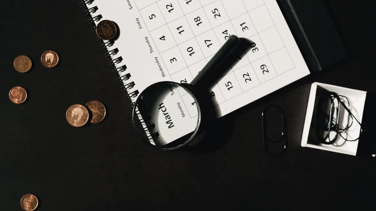 Magnifying glass on desk with calendar and documents