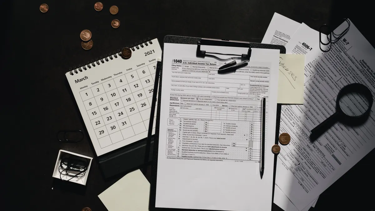 Clipboard with forms, calendar, and magnifying glass on desk