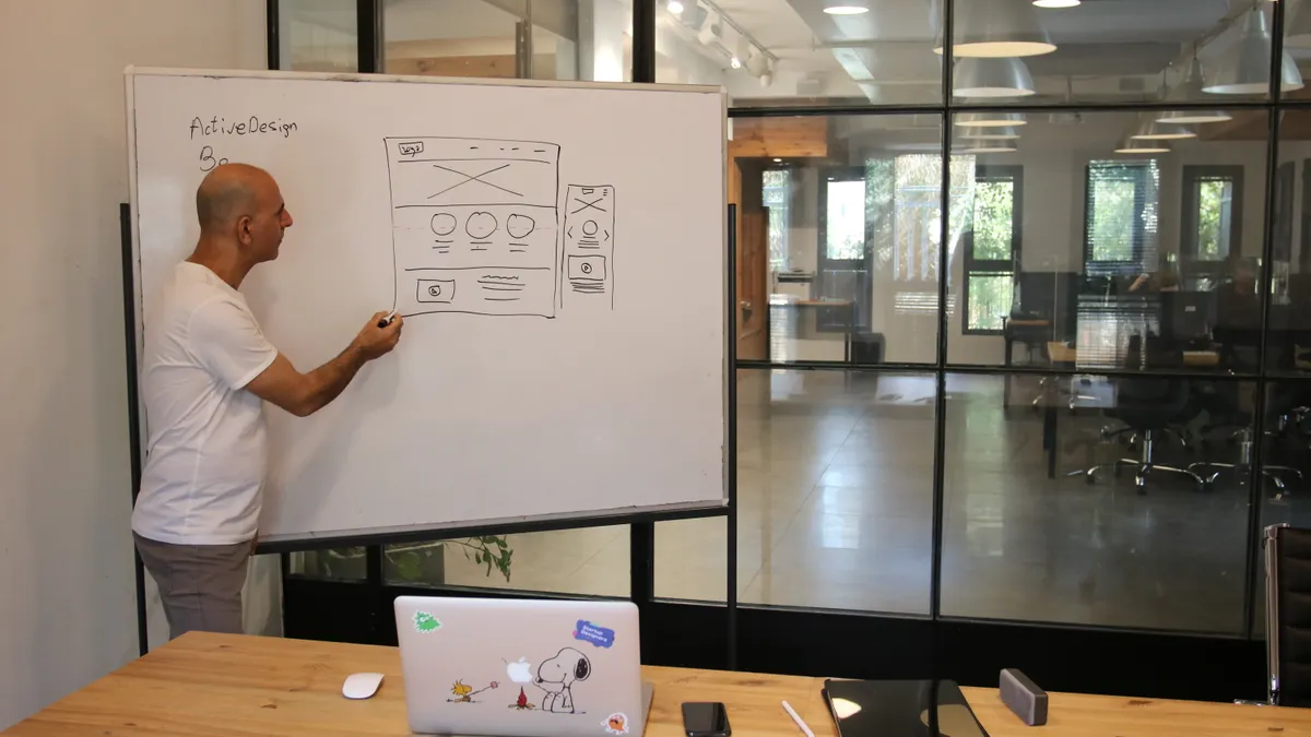 Person drawing a website wireframe on a whiteboard