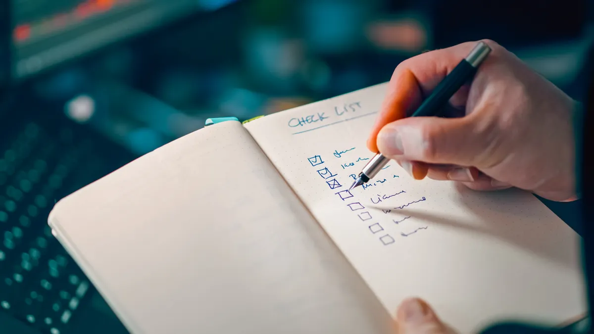 Hand checking items off a notebook checklist