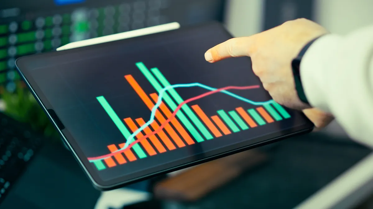 Hand pointing at a tablet with analytics graphs