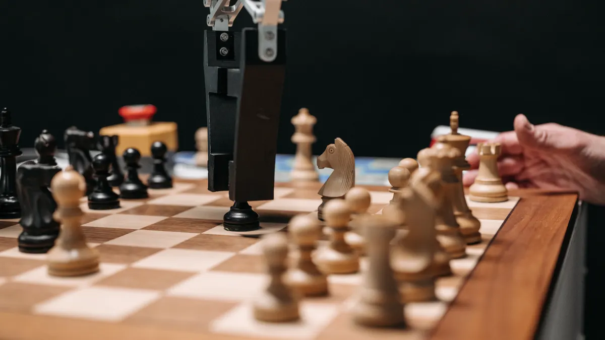 robotic arm and human hand over a chessboard